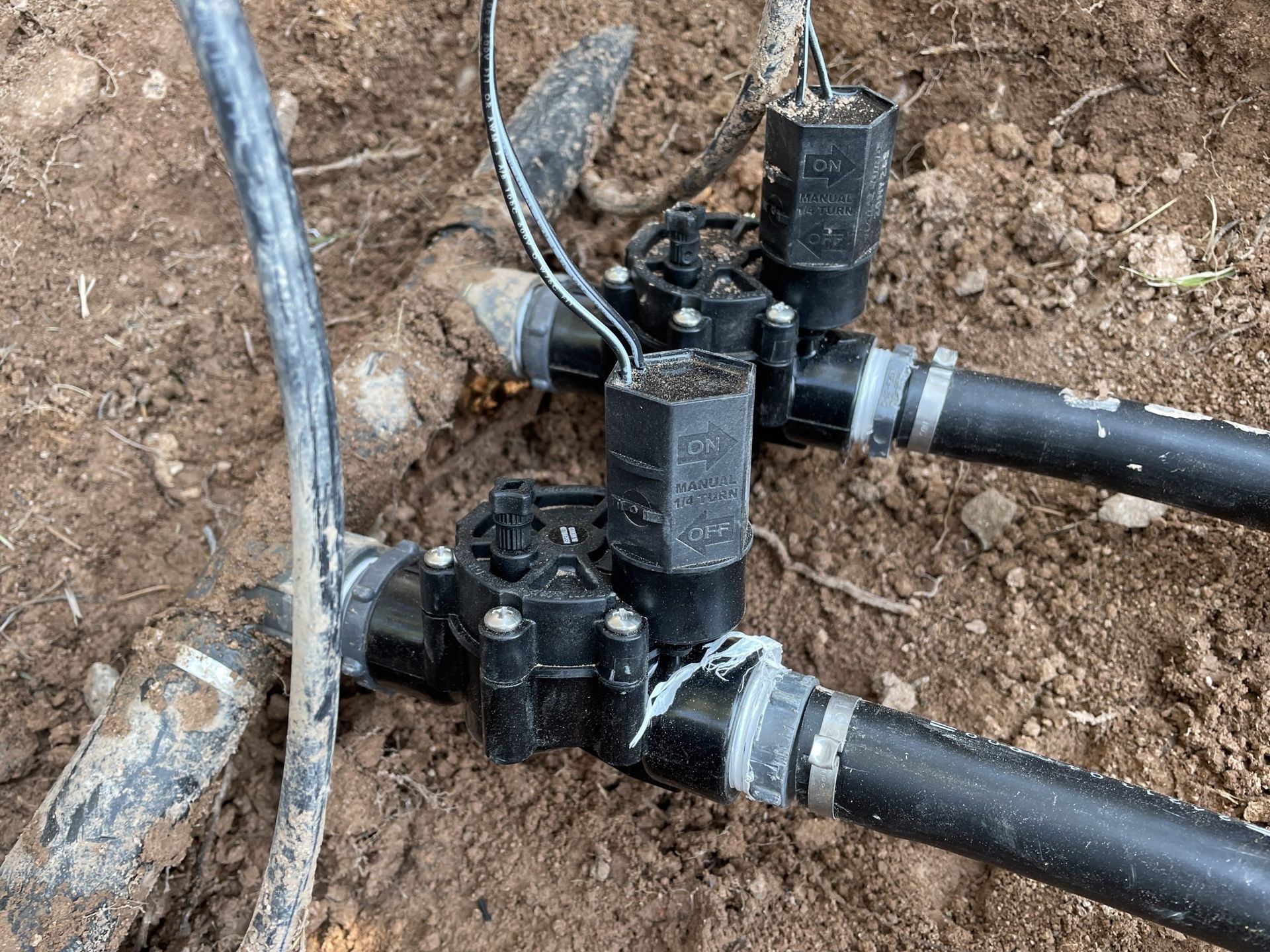A close up of a sprinkler system in the dirt.