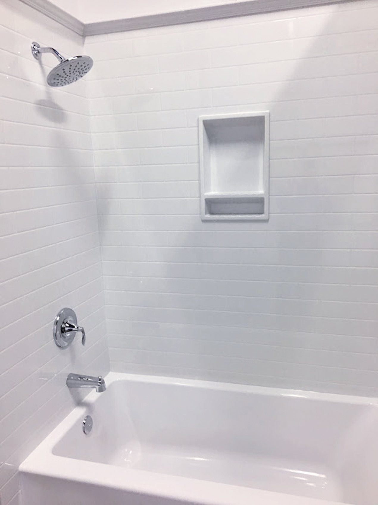 There is a bathtub in the shower with a shower head.