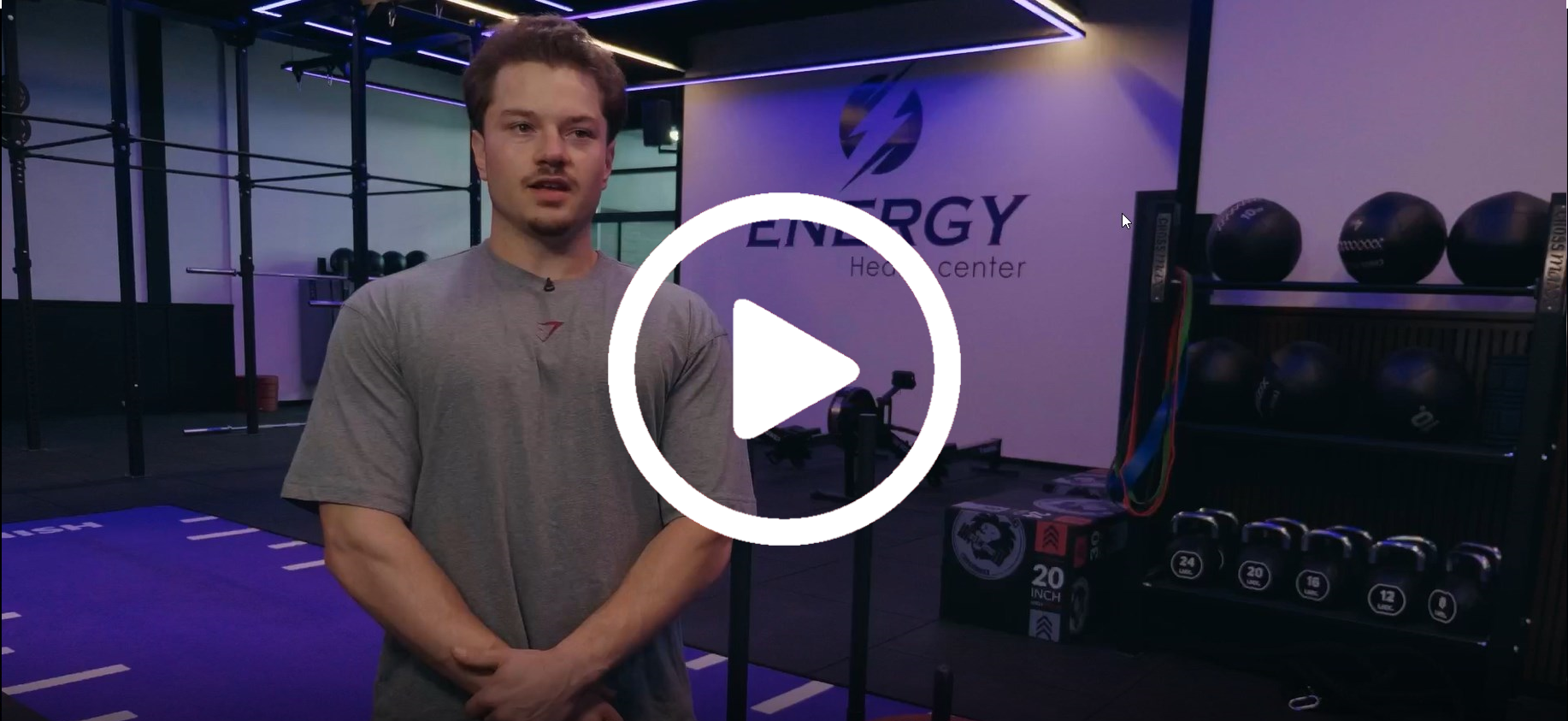 Een man staat voor een afspeelknop in een sportschool.