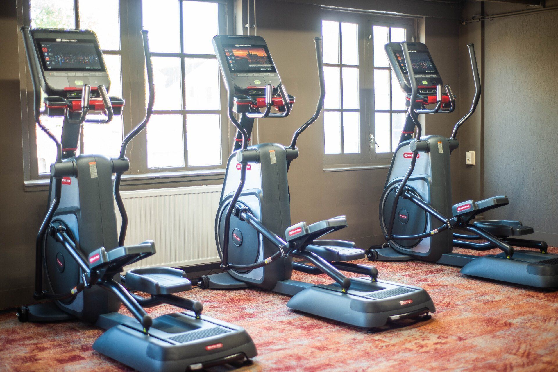 In een sportschool staan drie elliptische machines op een rij.