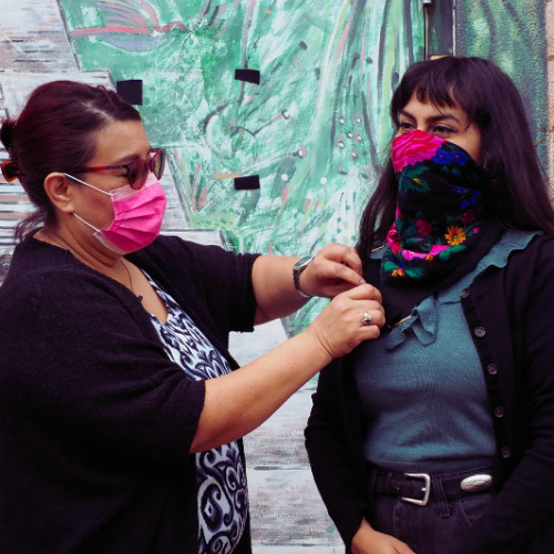 Two women wearing face masks are standing next to each other