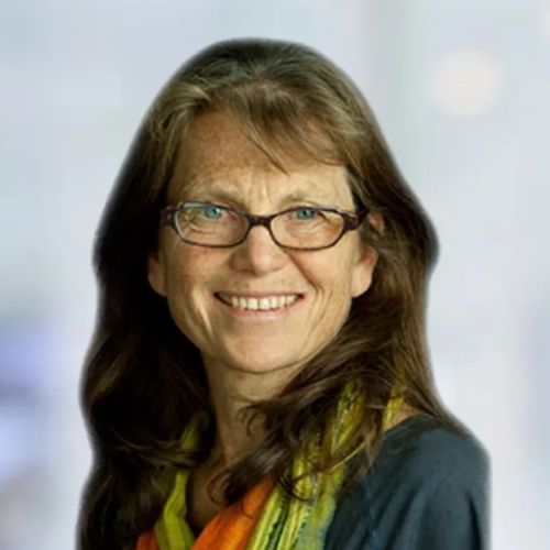 A woman wearing glasses and a scarf is smiling for the camera.