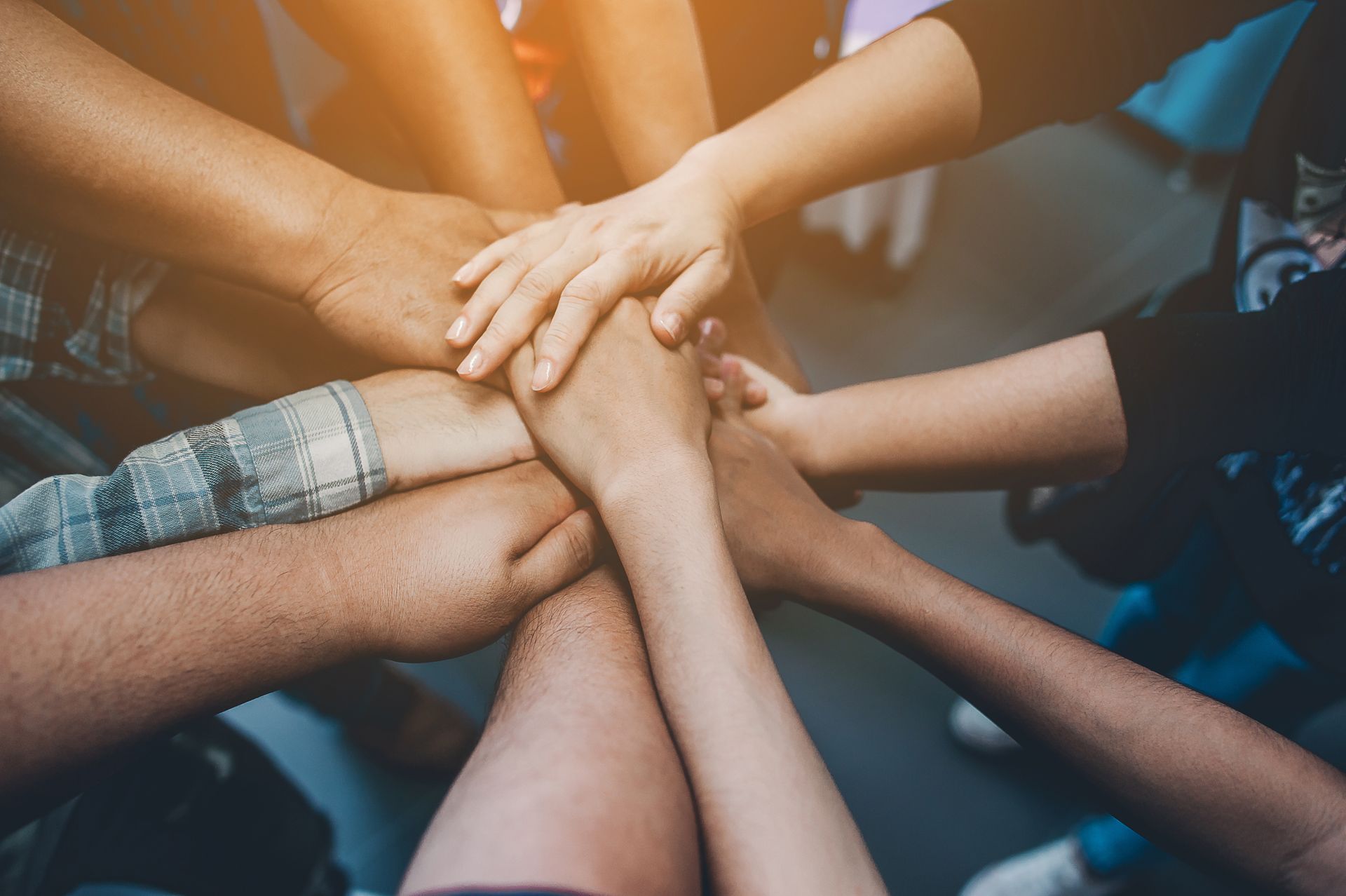 A group of people are putting their hands together in a circle.