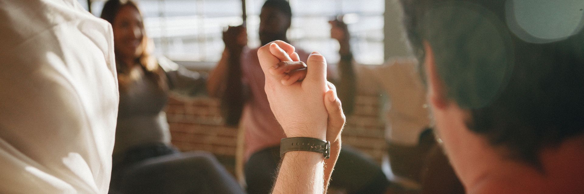 A group of people are sitting in a circle holding hands.