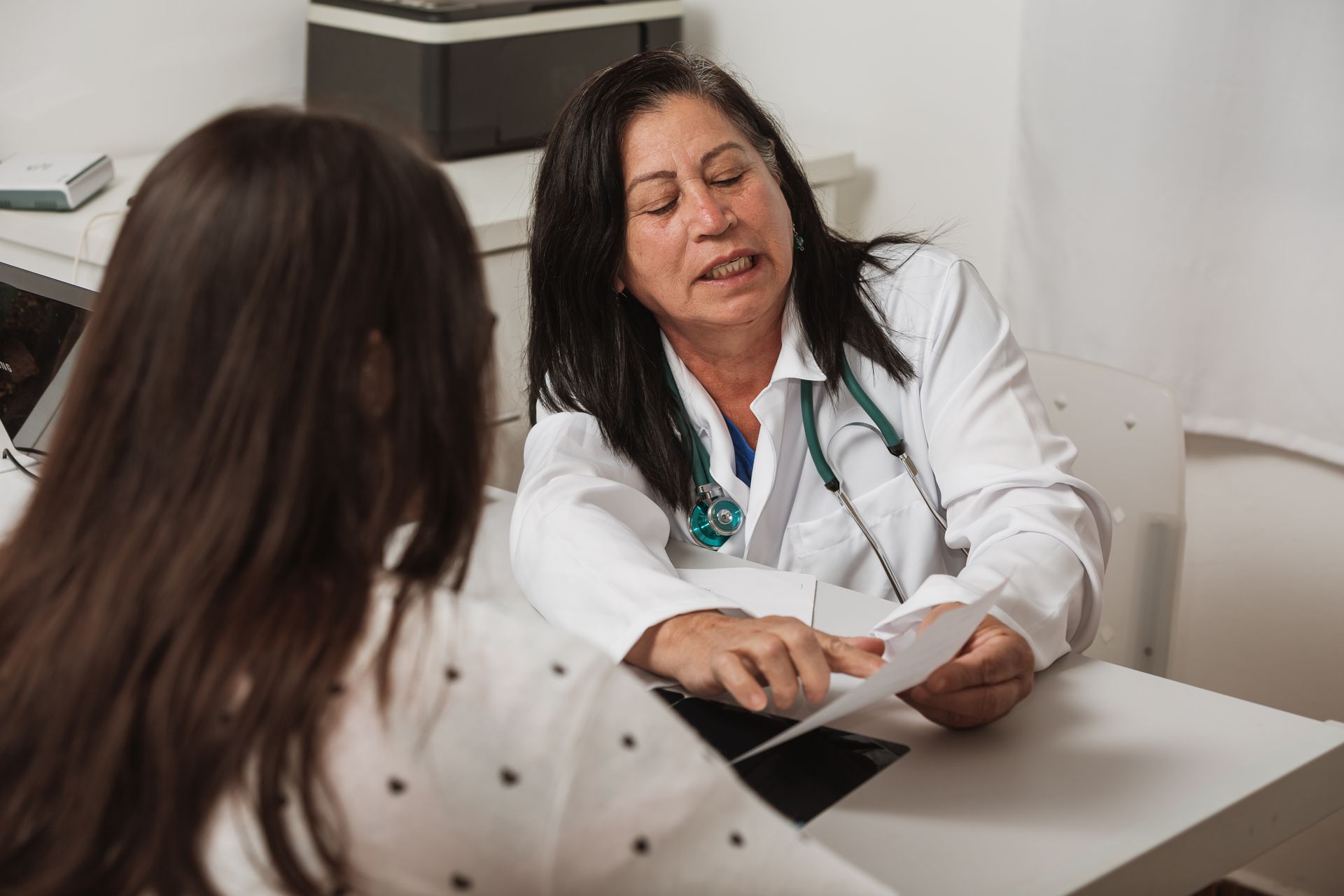 A woman is sitting at a table talking to a doctor.