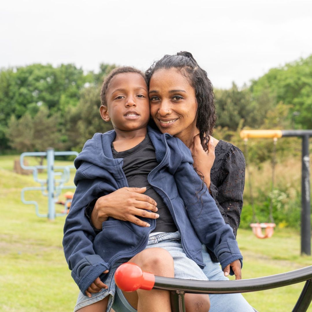 A woman is sitting on a seesaw holding a child