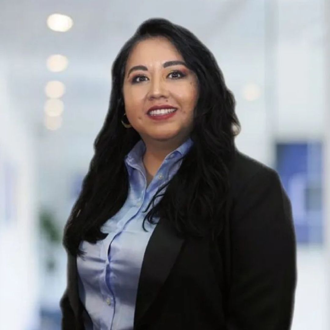 A woman in a suit and blue shirt is smiling for the camera.