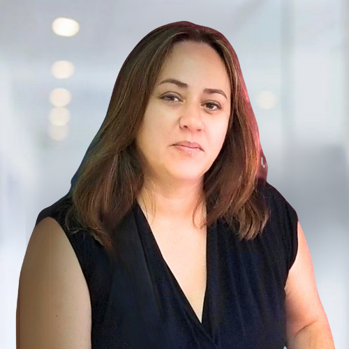 A woman in a black dress is standing in a room and looking at the camera.