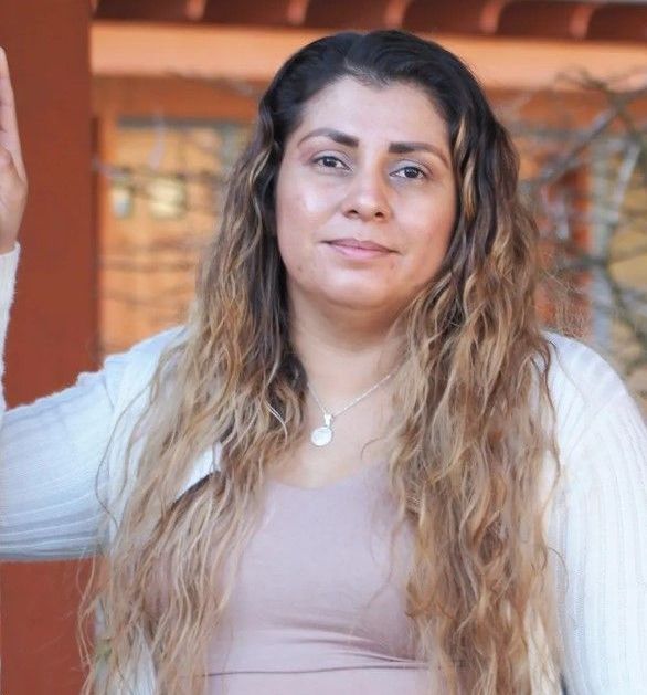 A woman with long hair is wearing a white sweater and a pink tank top