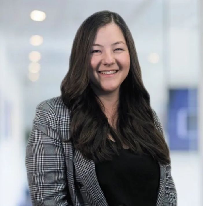 A woman in a plaid jacket is smiling for the camera