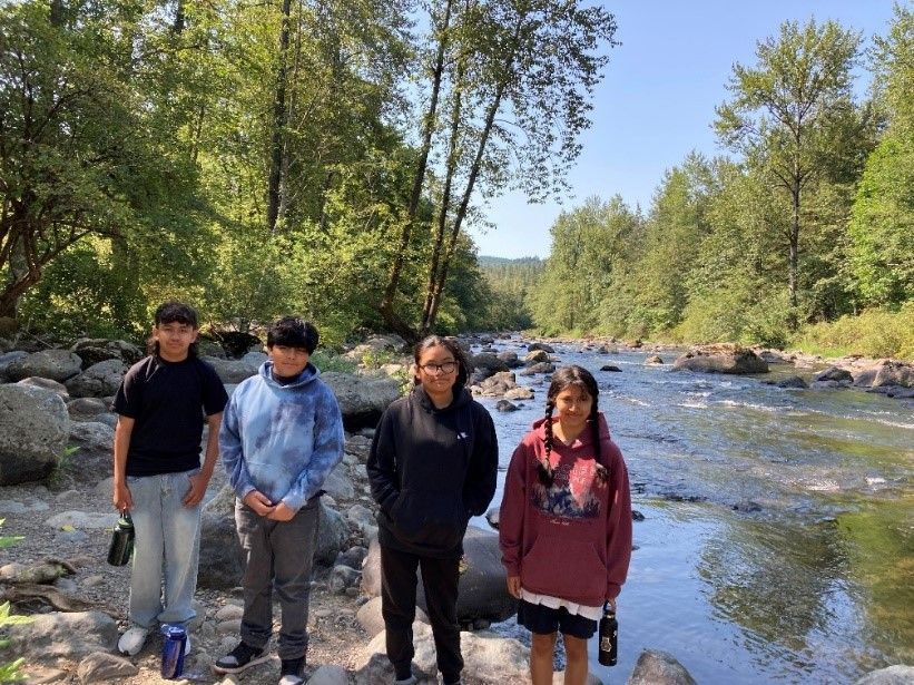 A group of young people are standing next to a river.
