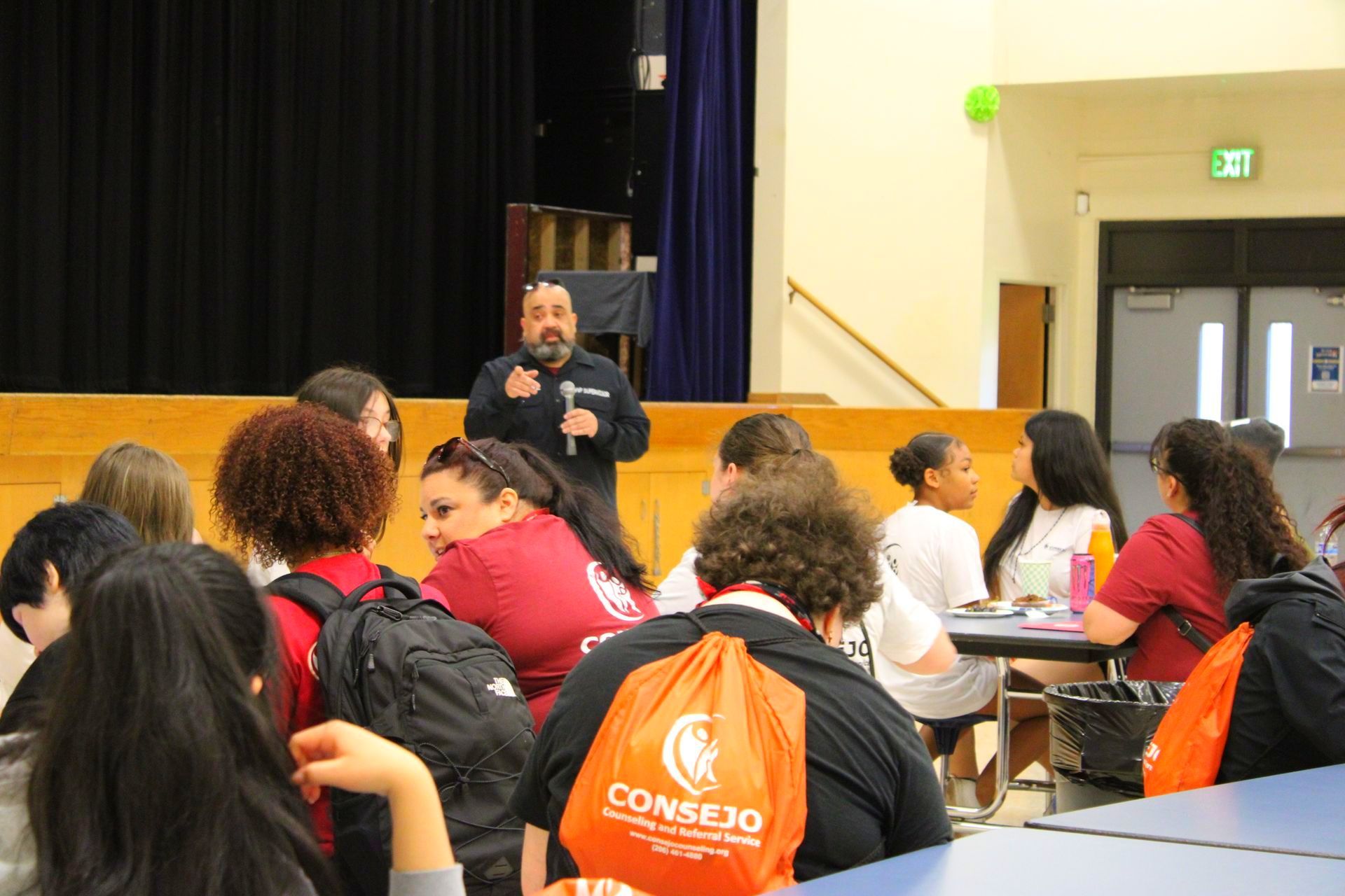 A man is giving a presentation to a group of people sitting at tables.