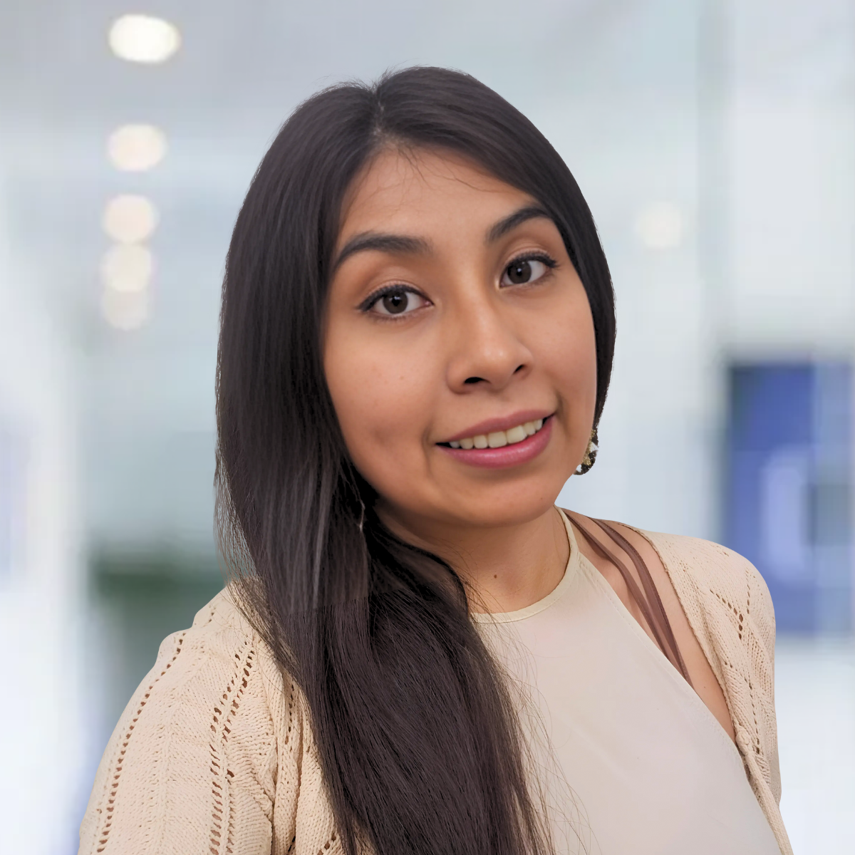 A woman wearing a striped shirt and a necklace smiles for the camera