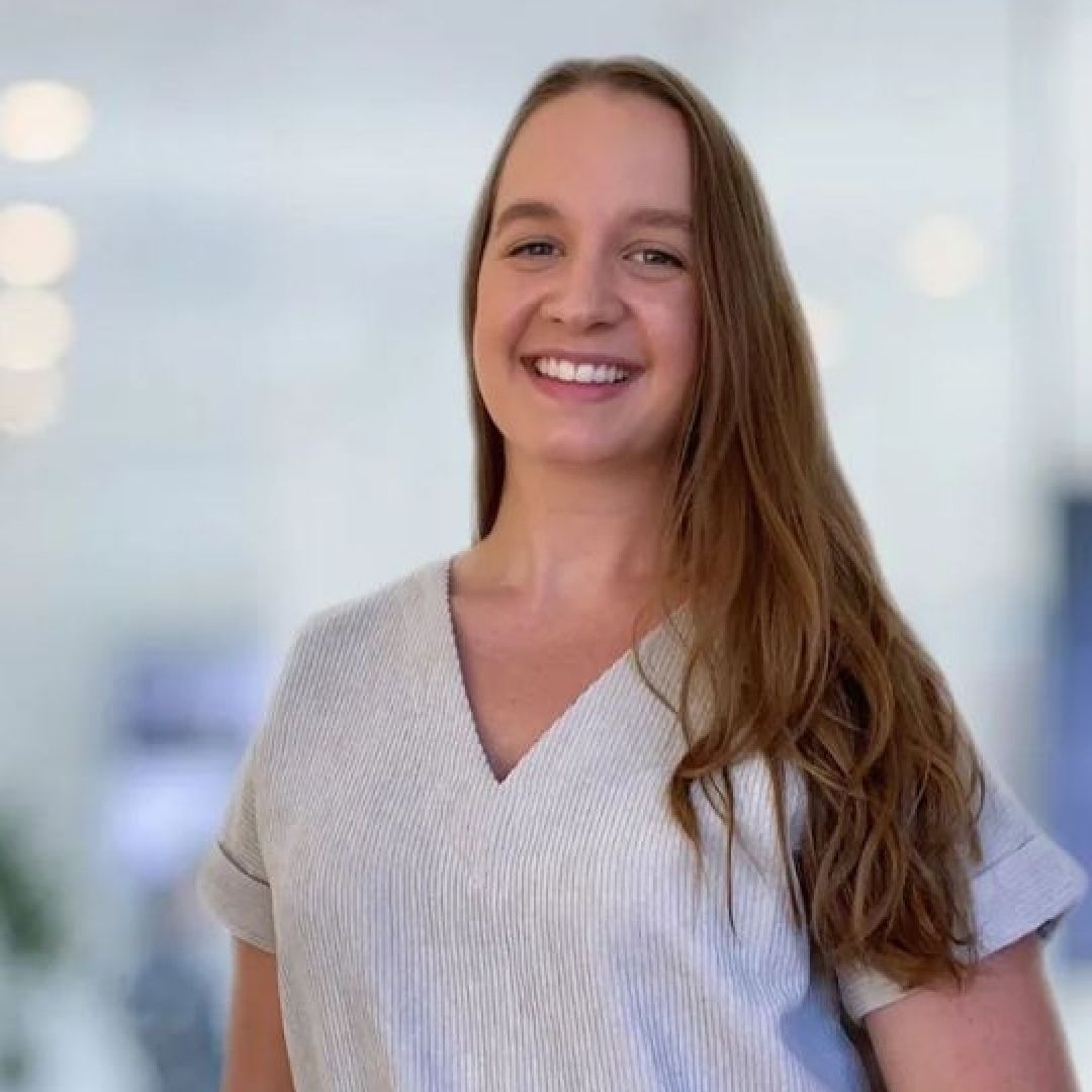 A woman in a white scrub top is smiling for the camera.