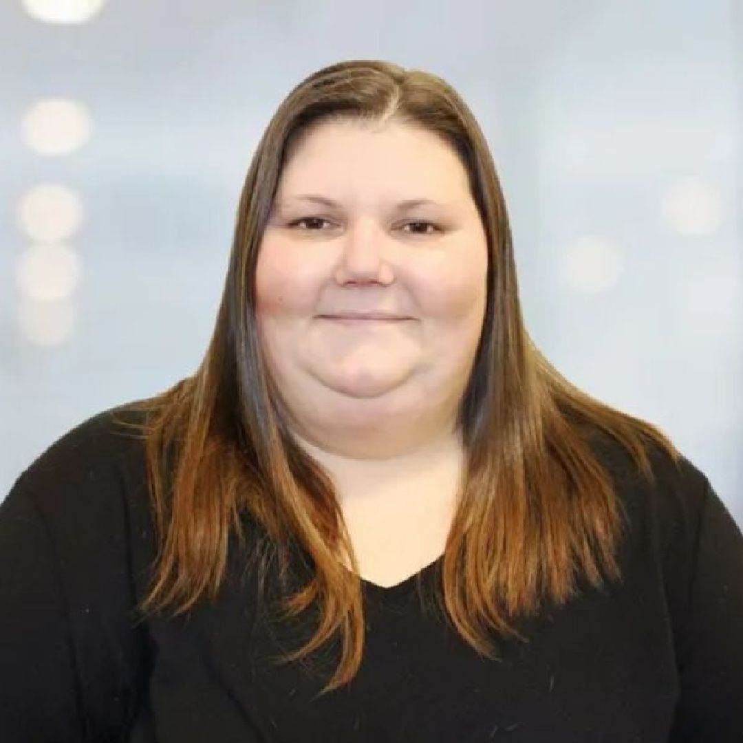 A woman with long hair is wearing a black shirt and smiling for the camera.