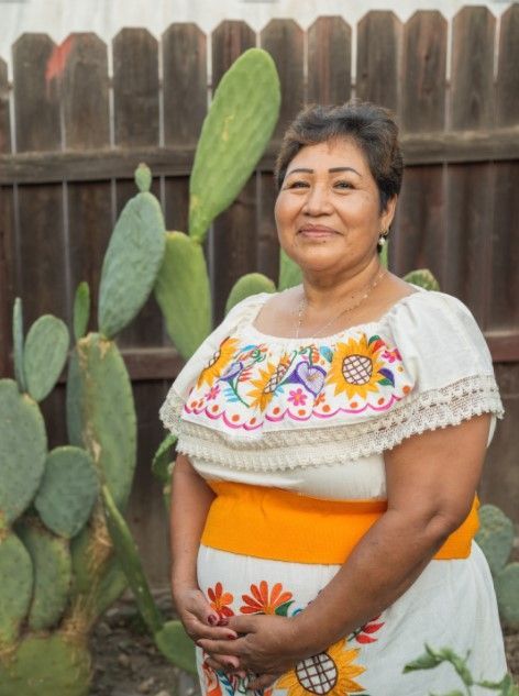 A woman in a white dress is standing in front of a cactus.