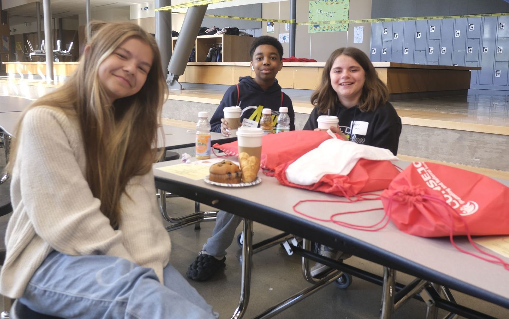 A group of young people are sitting at a table in a school cafeteria.