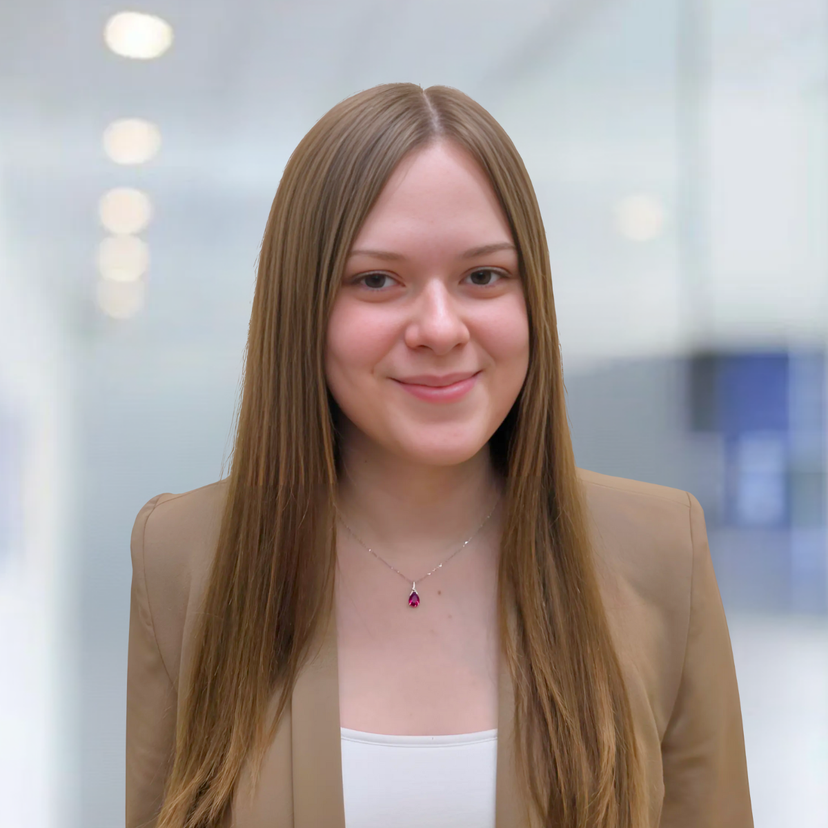 A woman wearing a striped shirt and a necklace smiles for the camera