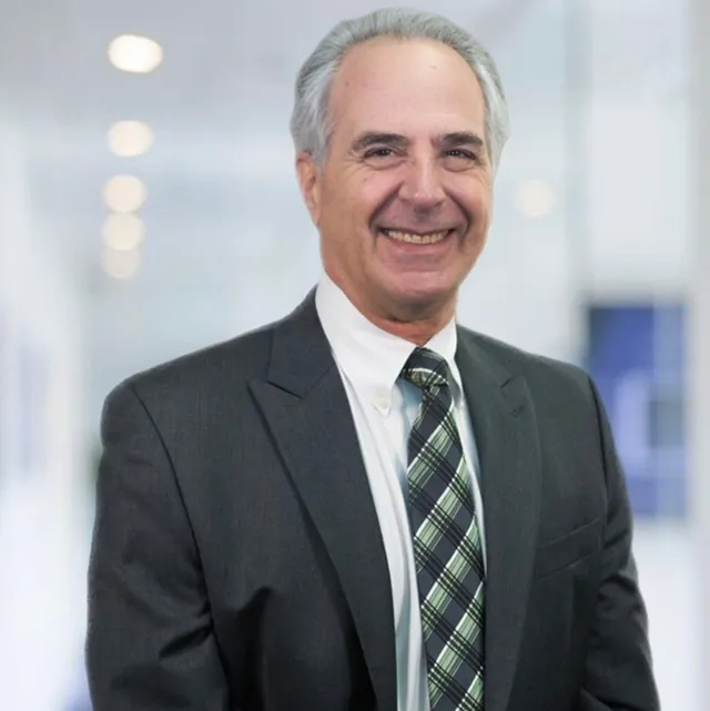 A man in a suit and tie is smiling for the camera