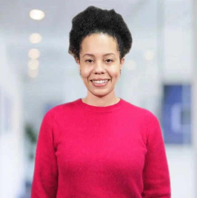 A woman in a red sweater is smiling for the camera