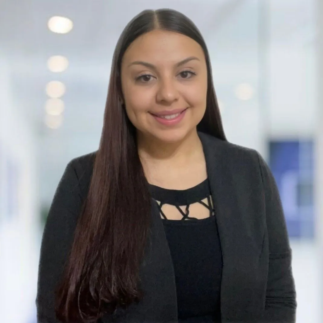 A woman with long dark hair is smiling for the camera