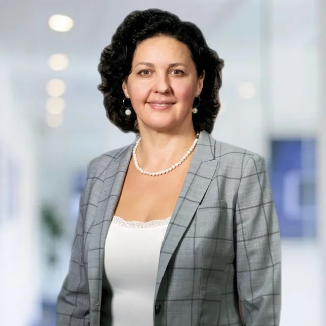 A woman wearing a plaid jacket and a pearl necklace