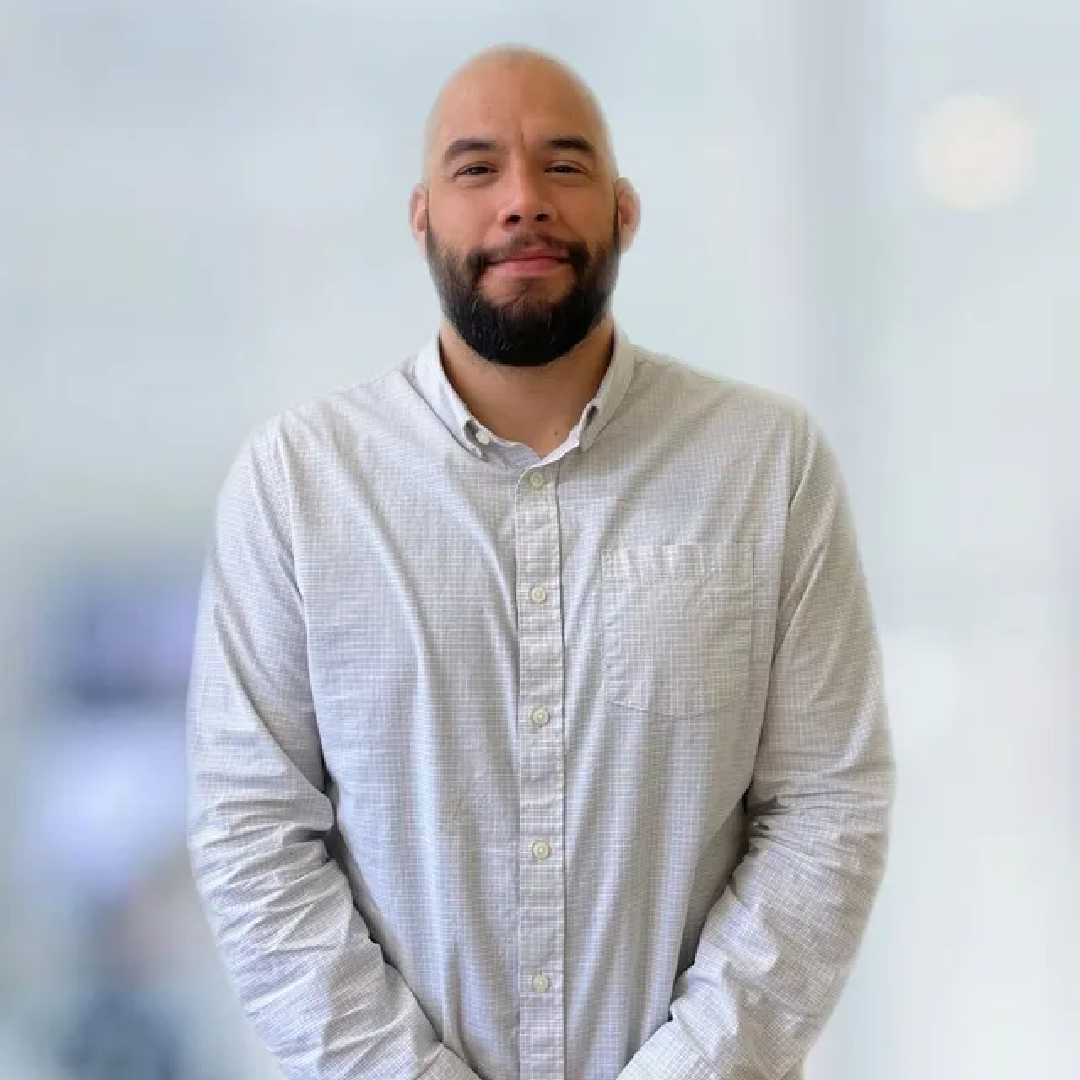 A bald man with a beard is wearing a white shirt.