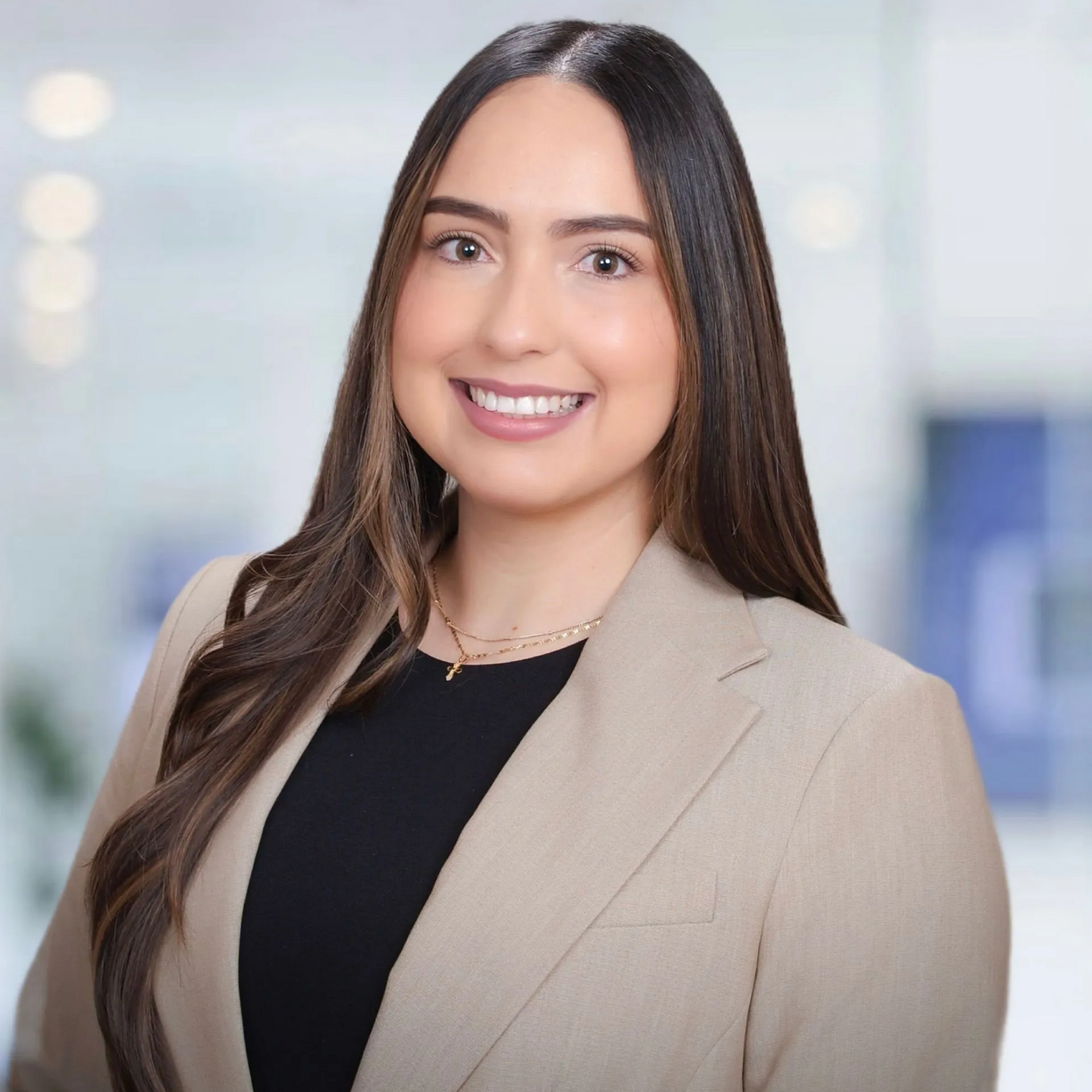 A woman in a tan jacket and black shirt is smiling for the camera.