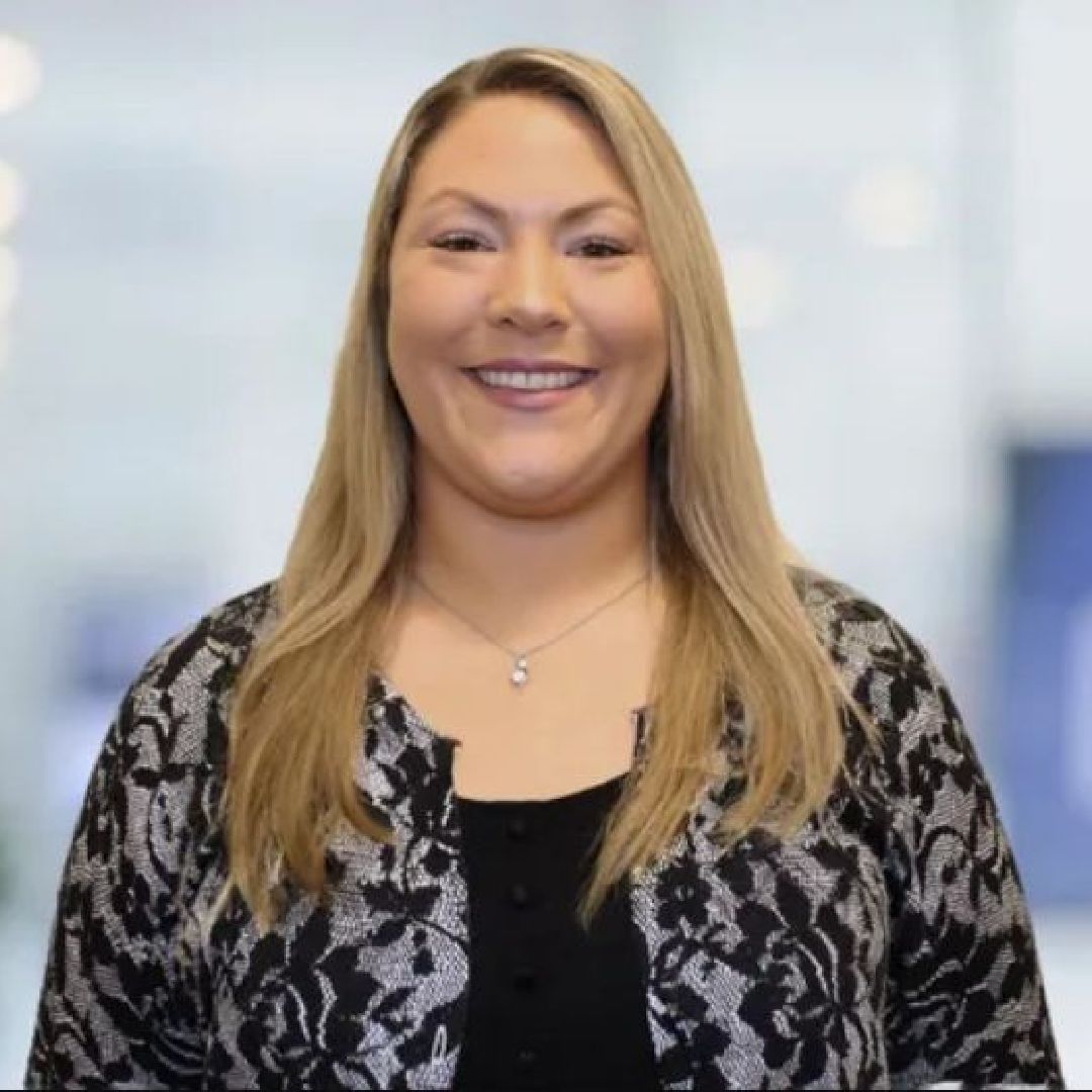 A woman with long blonde hair is smiling for the camera