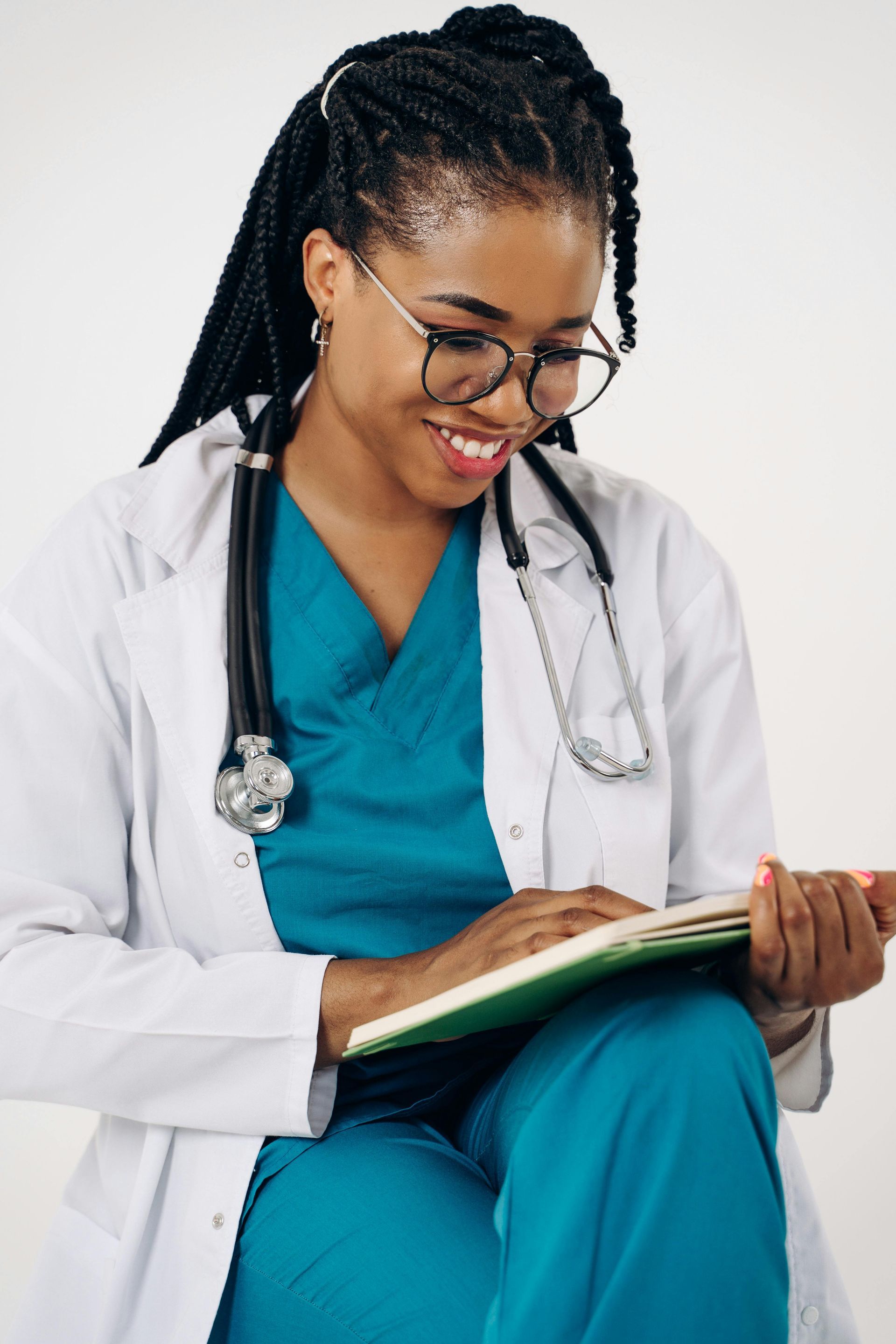 A female doctor with a stethoscope around her neck is reading a book.