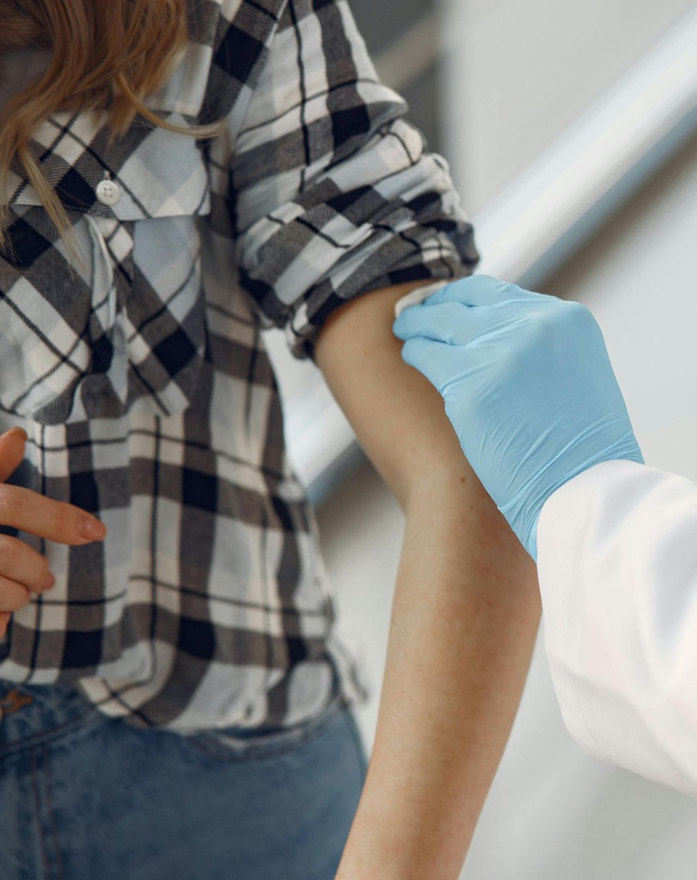 A woman in a plaid shirt is getting a vaccine from a doctor.