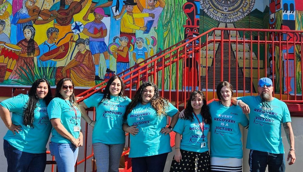 A group of people are posing for a picture in front of a mural.