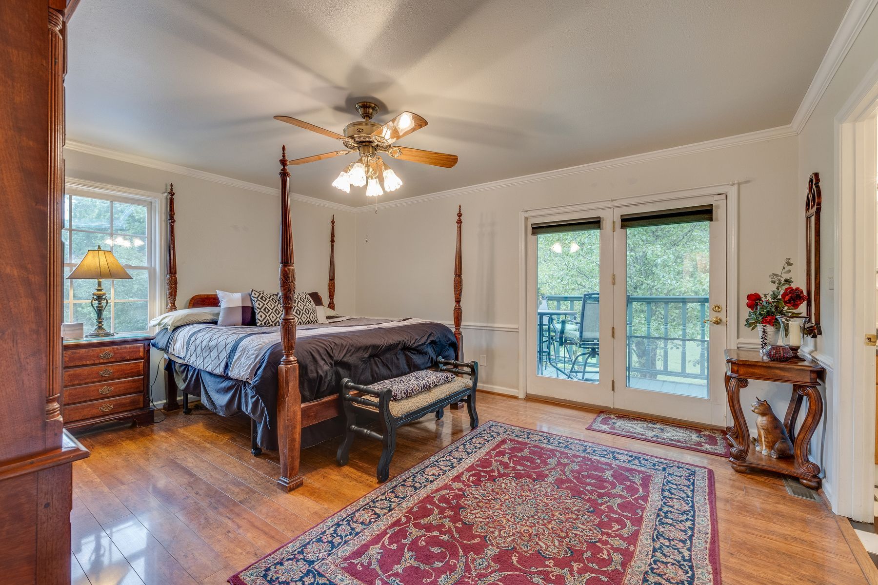 Bedroom with a four poster bed , a bench , a rug and a ceiling fan.