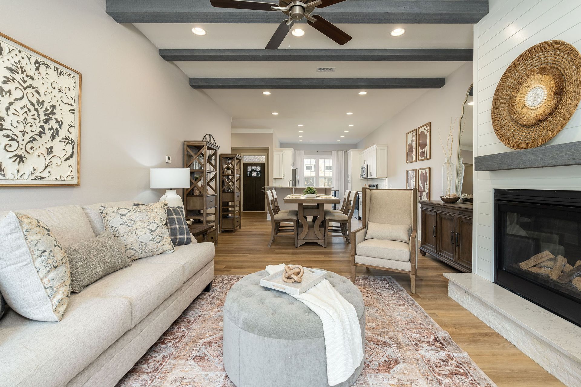 A living room with a couch , chair , ottoman and fireplace.