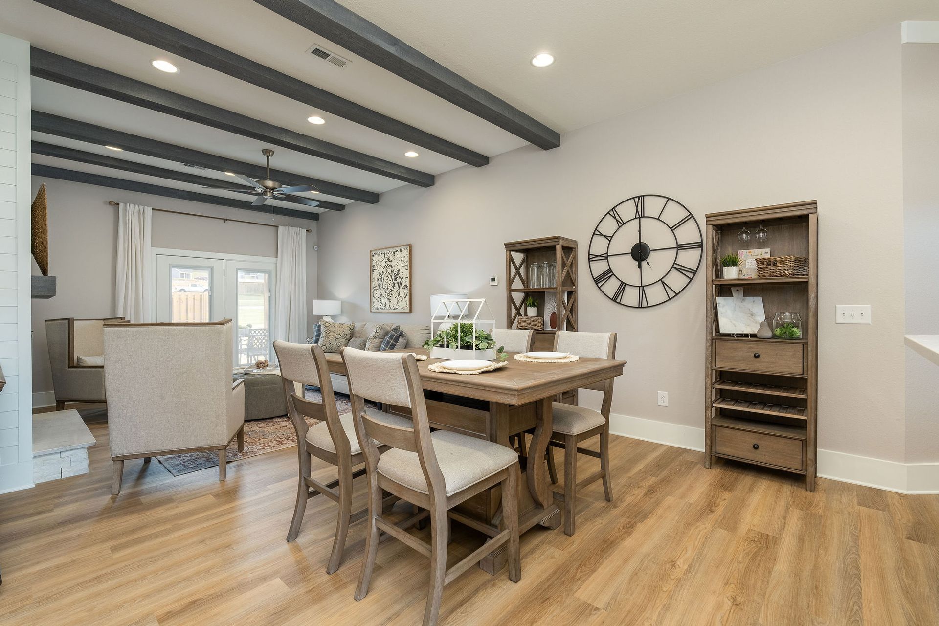 A dining room with a table and chairs and a clock on the wall.