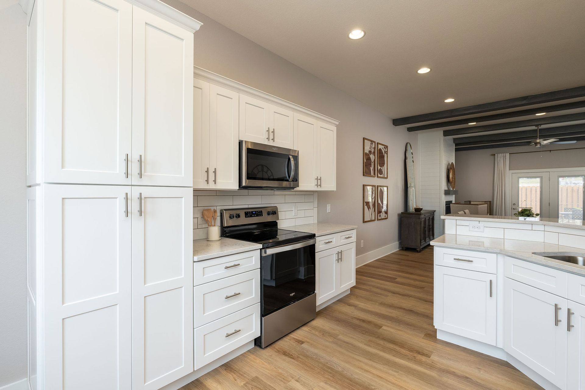 A kitchen with white cabinets , stainless steel appliances , and hardwood floors.