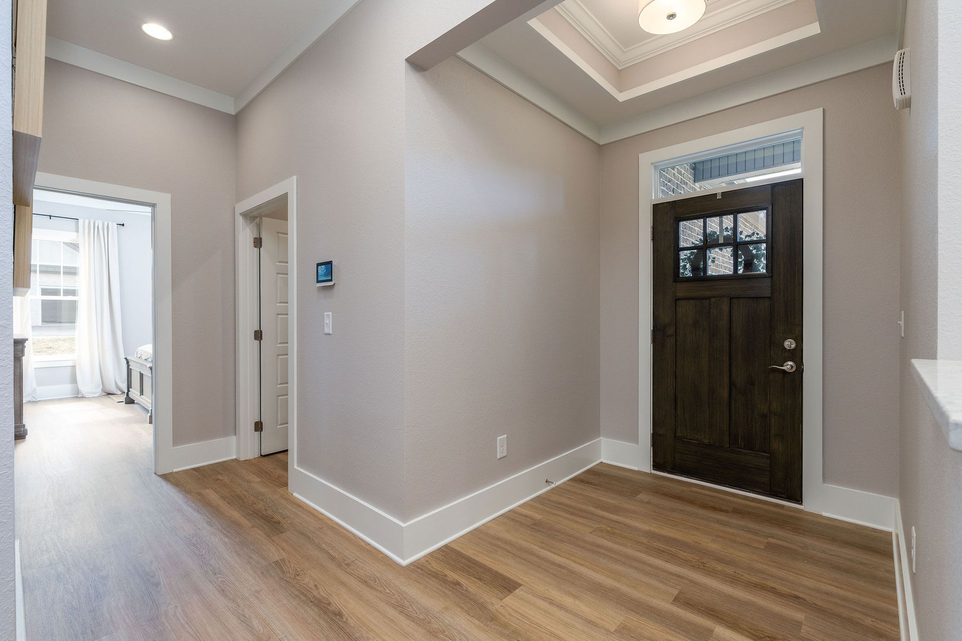 A hallway with hardwood floors and a black door in a house.