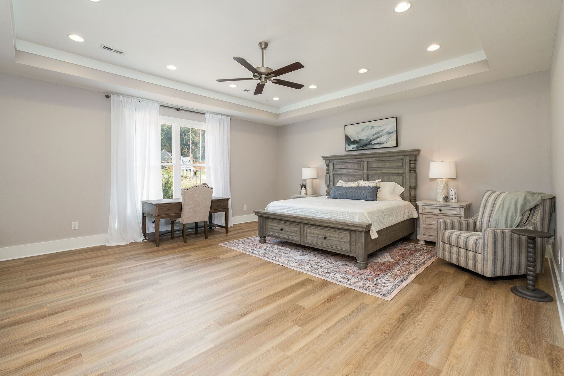 A bedroom with a bed , chair , desk and ceiling fan.