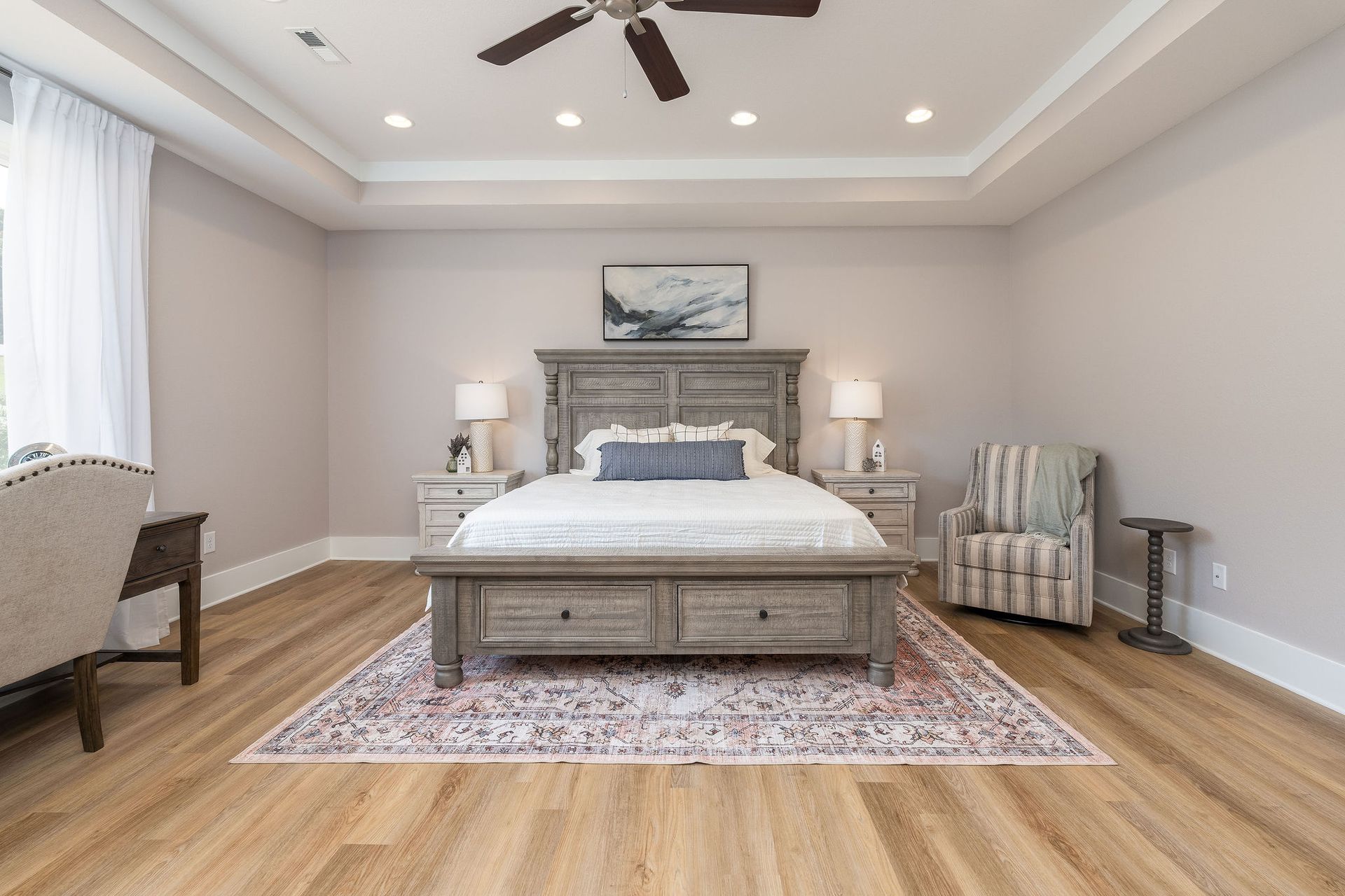 A bedroom with a bed , chair , desk and ceiling fan.