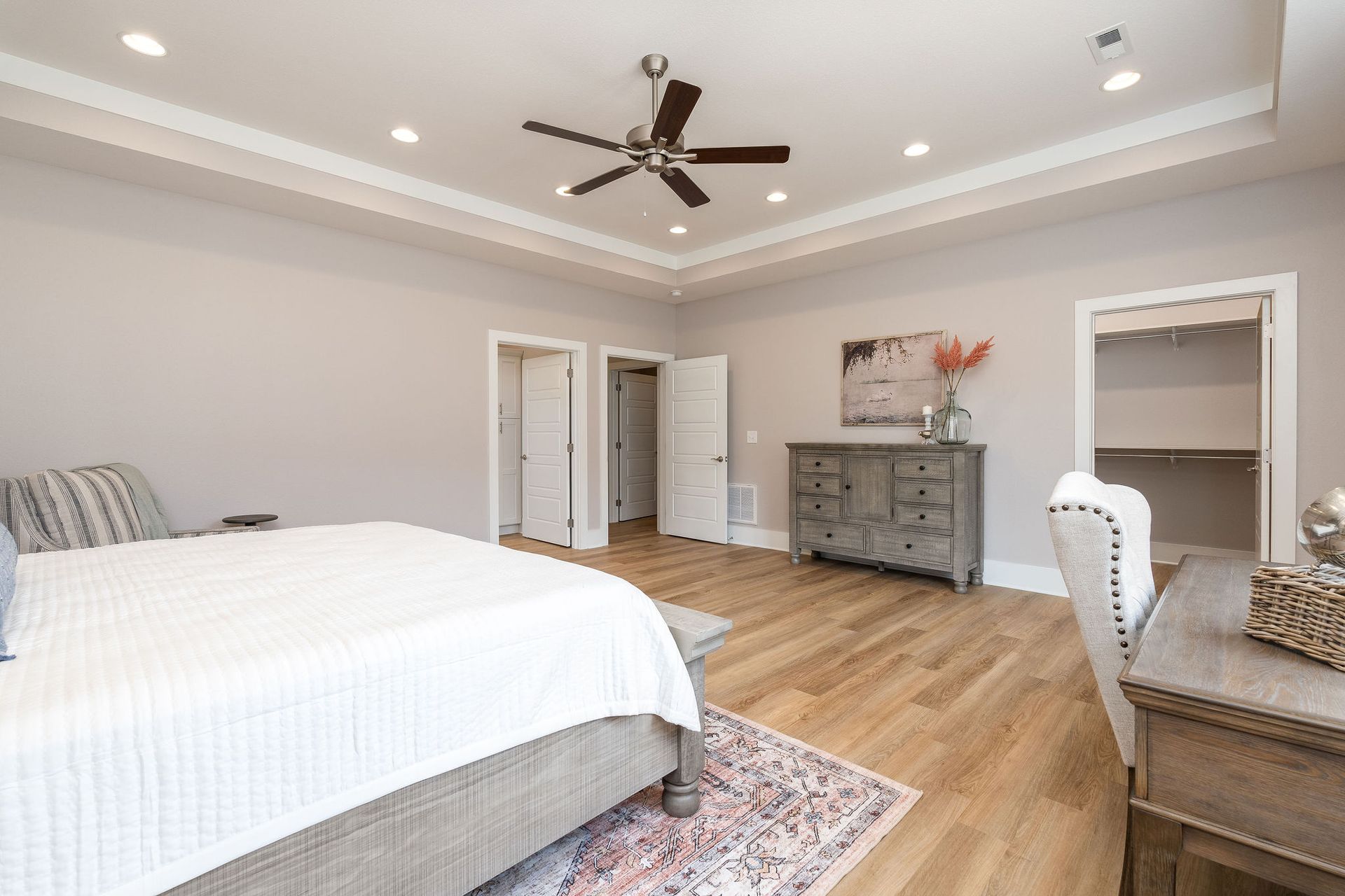 A bedroom with a bed , dresser , chair and ceiling fan.