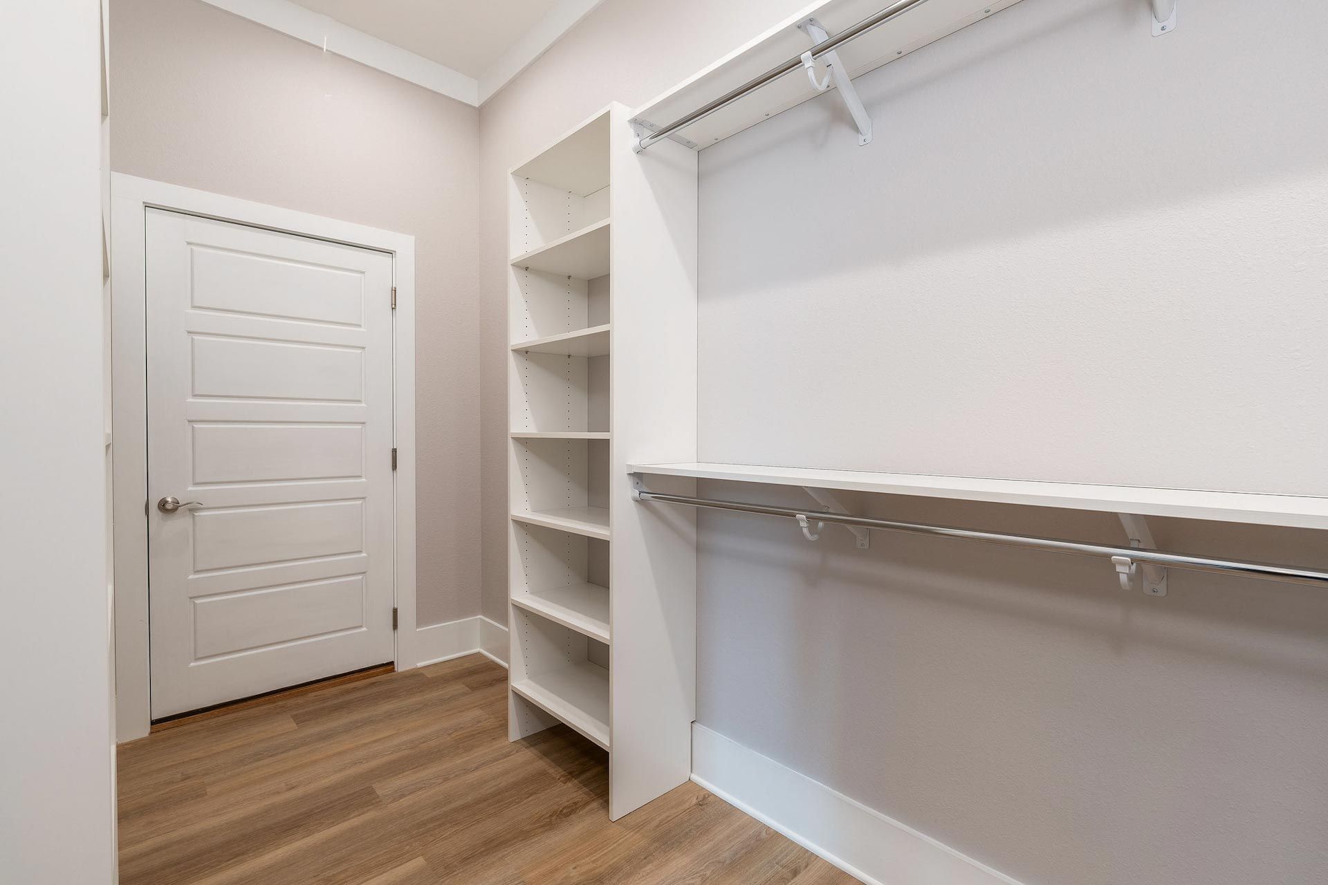 An empty walk in closet with shelves and a door.