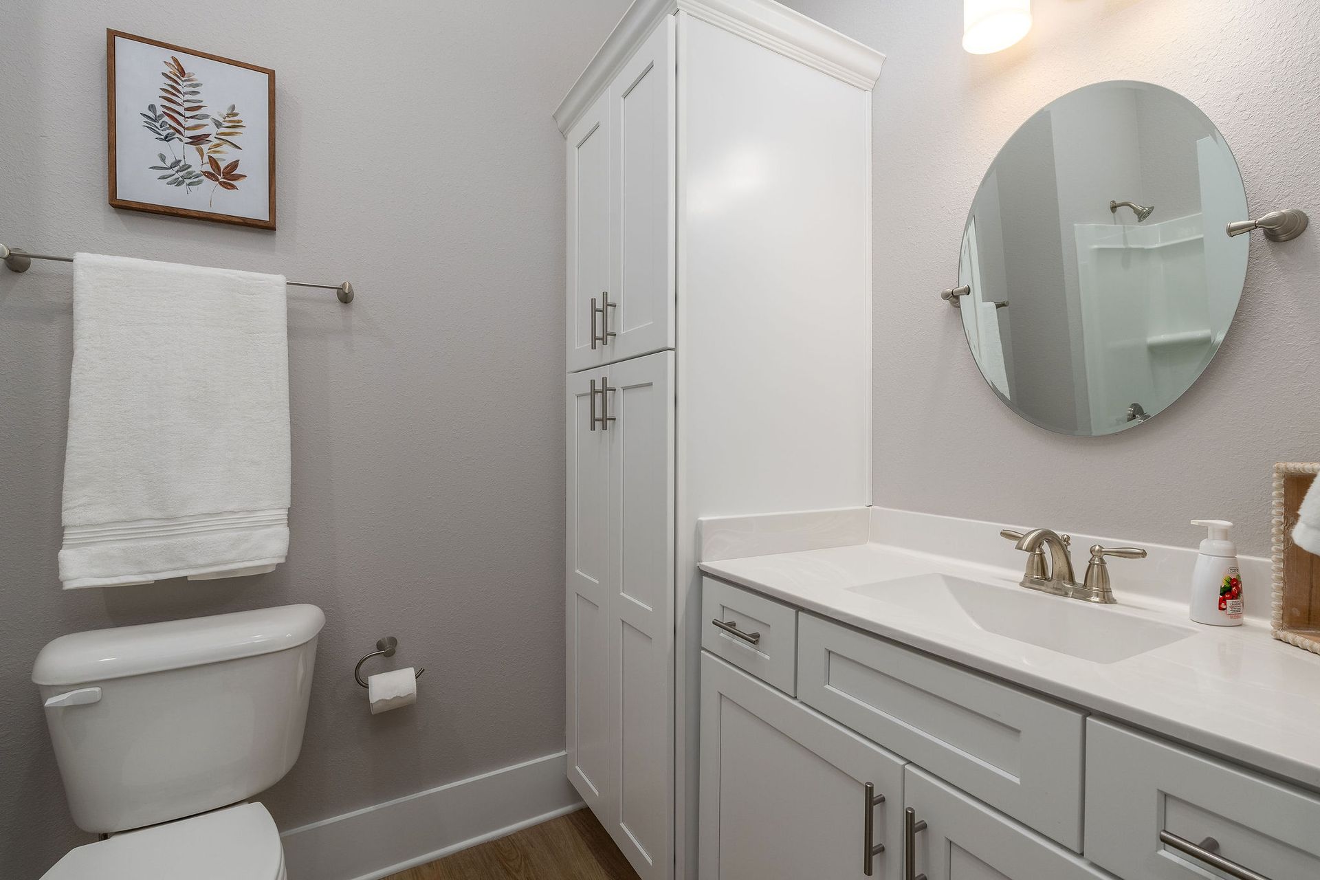 A bathroom with a toilet , sink and mirror.