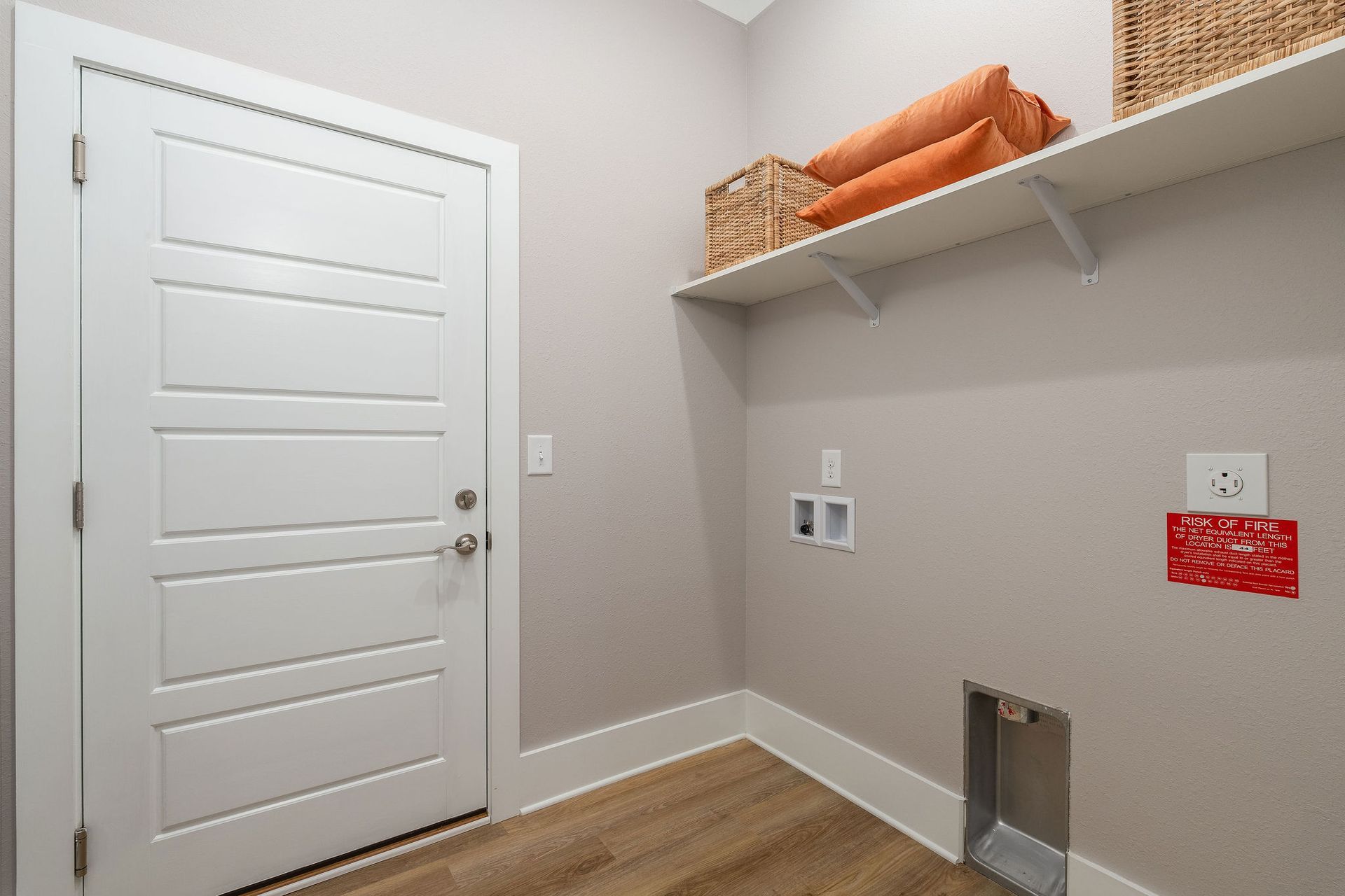 A laundry room with a door and a shelf.