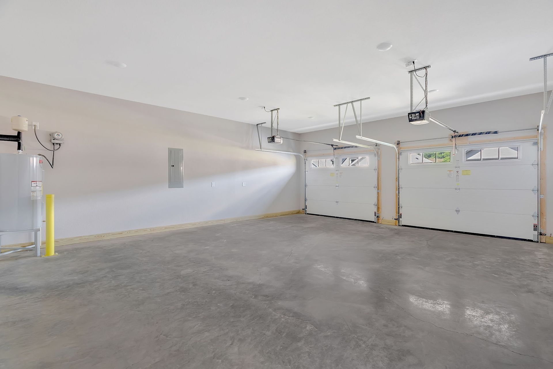 An empty garage with two garage doors and a ceiling fan.