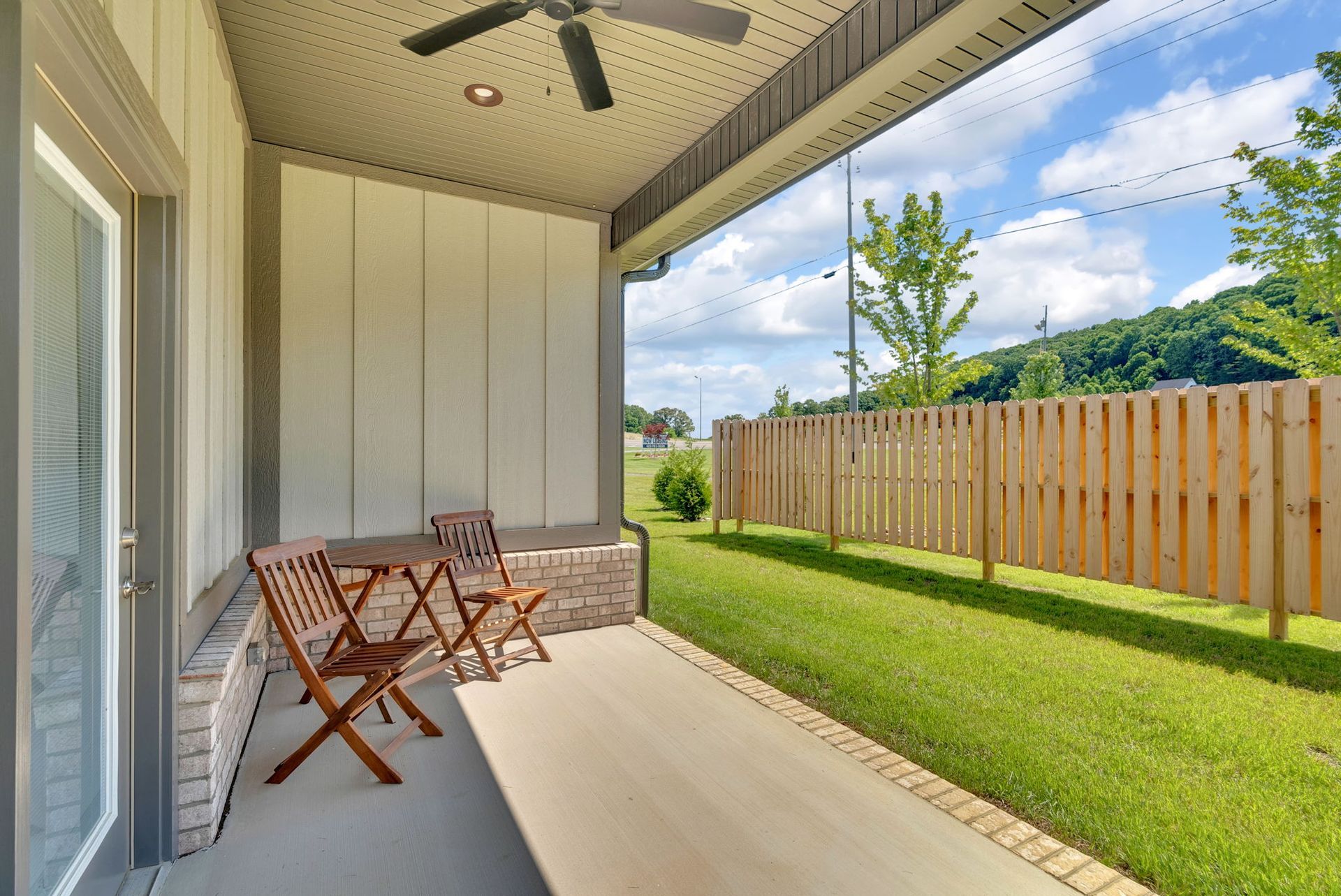 A porch with a table and chairs and a ceiling fan.