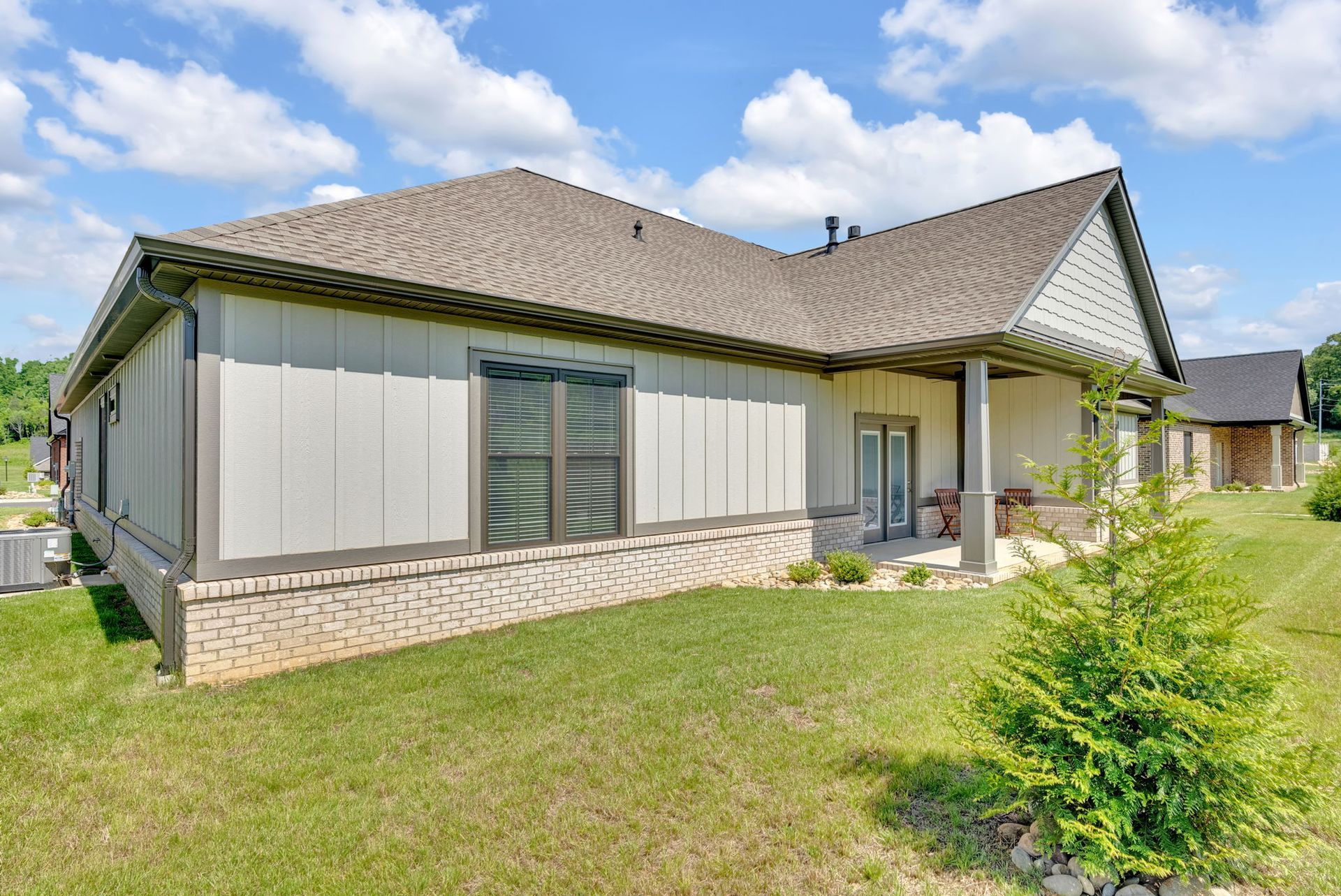 The back of a house with a porch and a lot of grass.