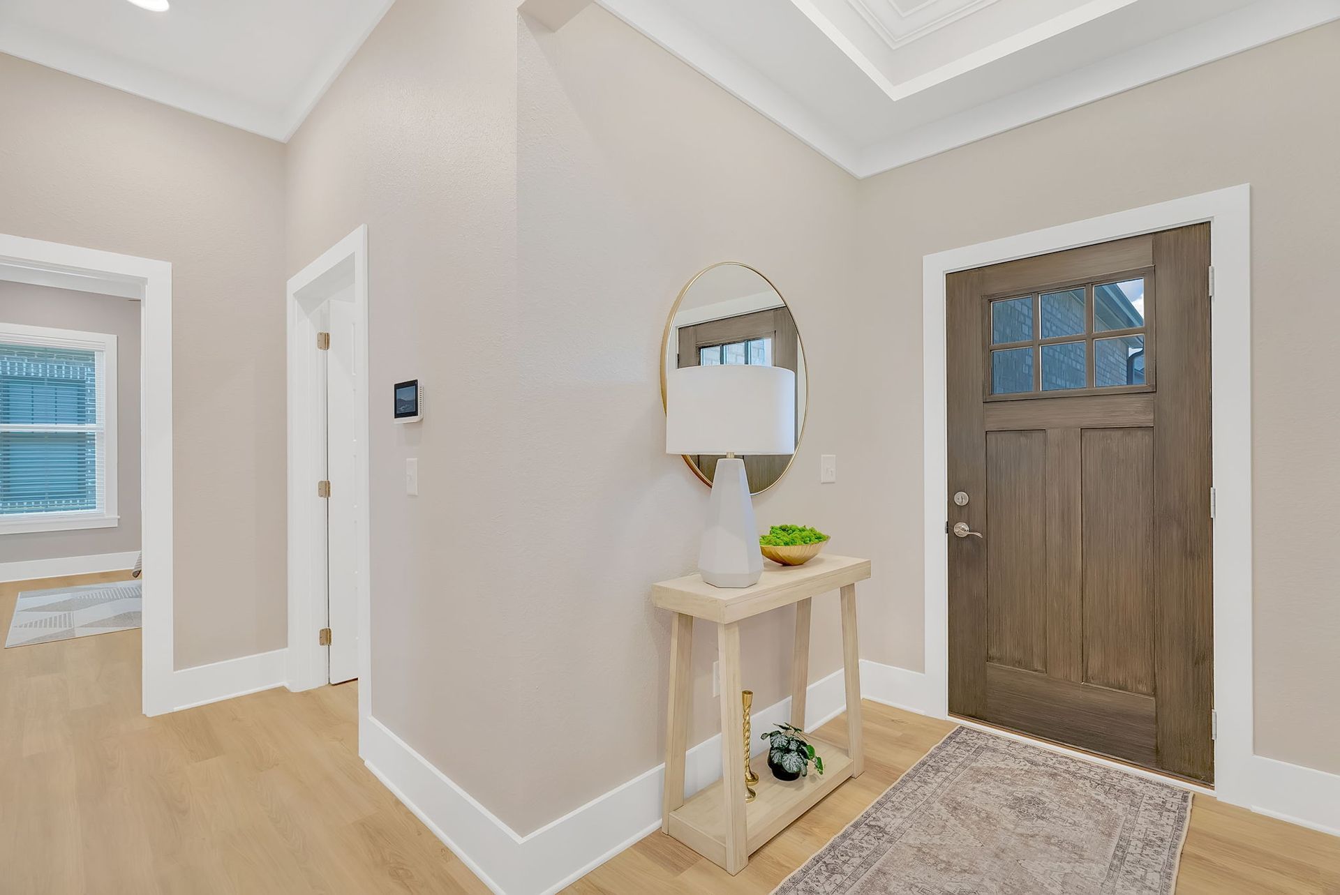 A hallway with a table and a mirror in front of a door.