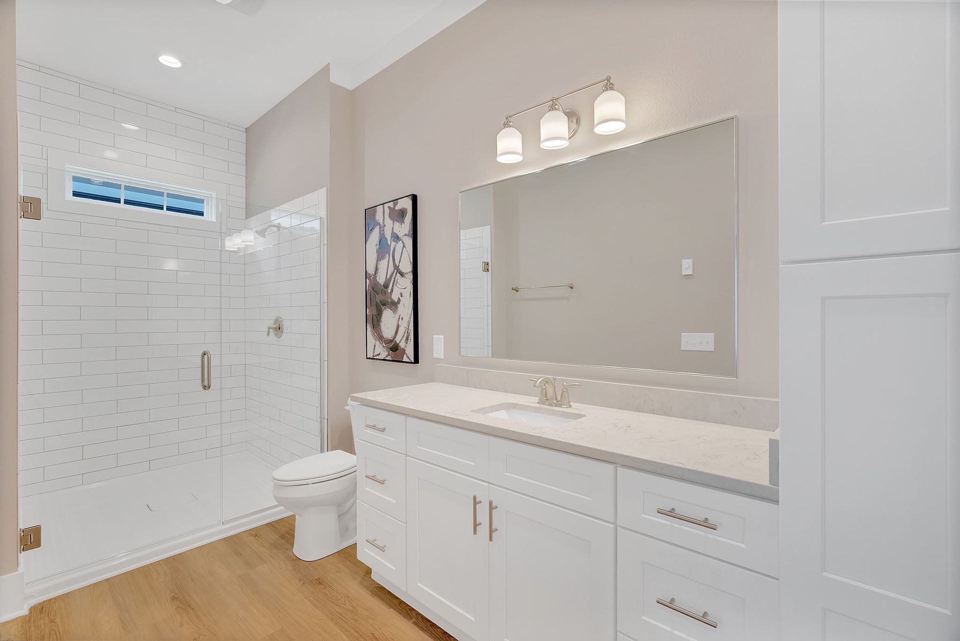 A bathroom with a toilet , sink , mirror and walk in shower.