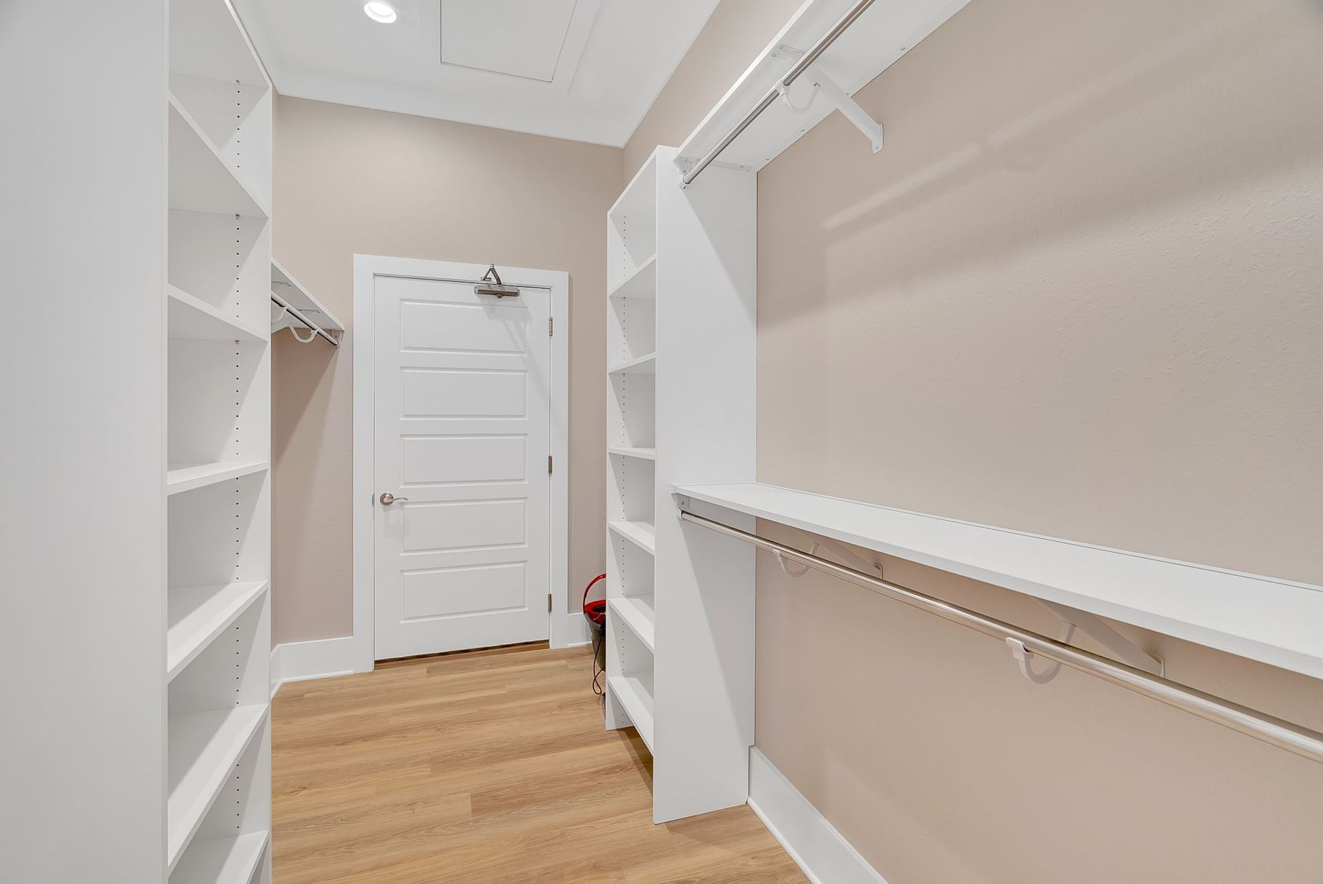 A walk in closet with lots of shelves and a door.