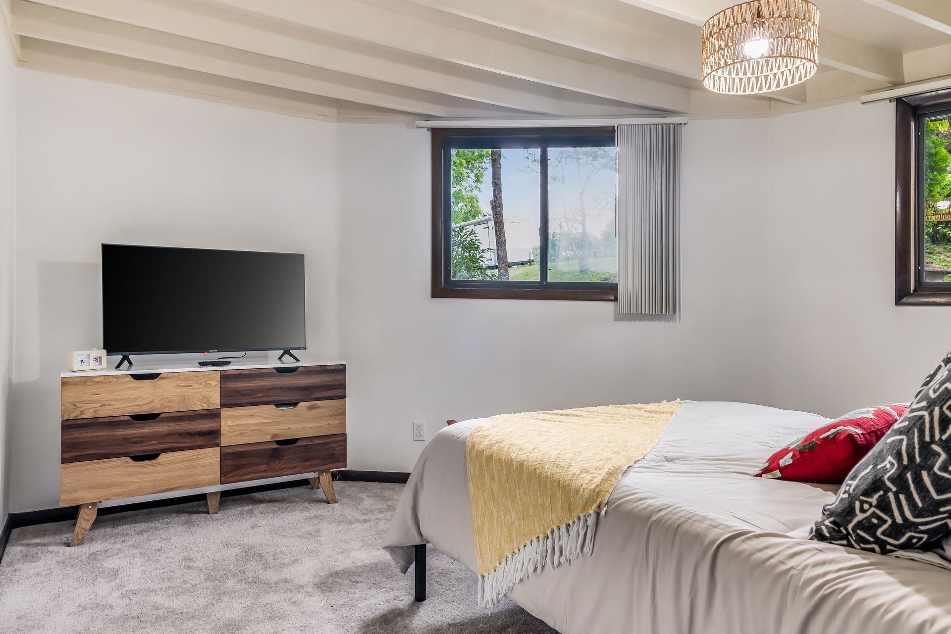 A bedroom with a bed , dresser , television and window.